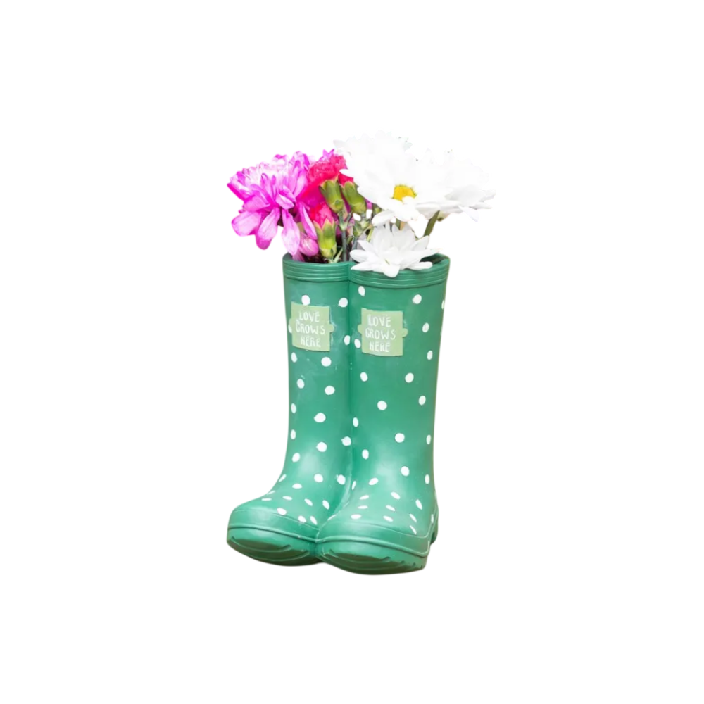 Green polka dot rain boot with flowers on a wooden surface